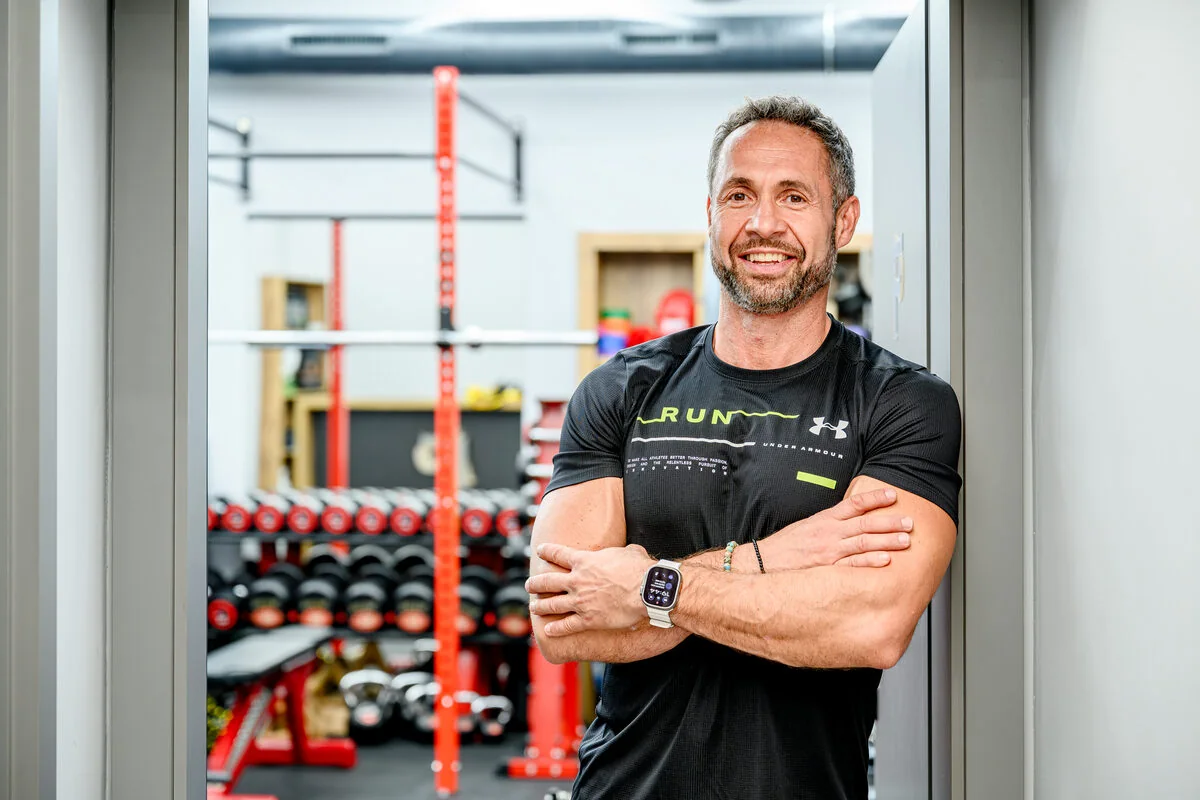 Štefan Bitto, lektor Fit Pilates, se založenýma rukama u vstupu do posilovny